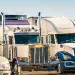 four white semi trucks parked in parking lot