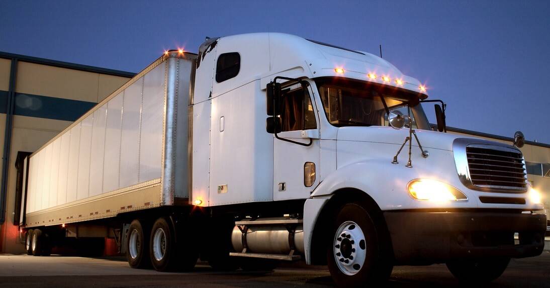 semi truck backed into a warehouse dock at night