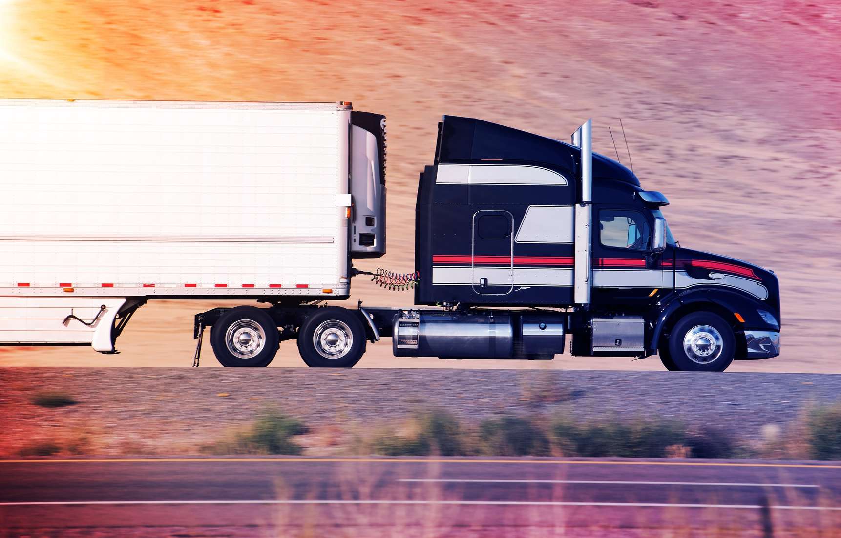 black and white striped semi truck driving down highway