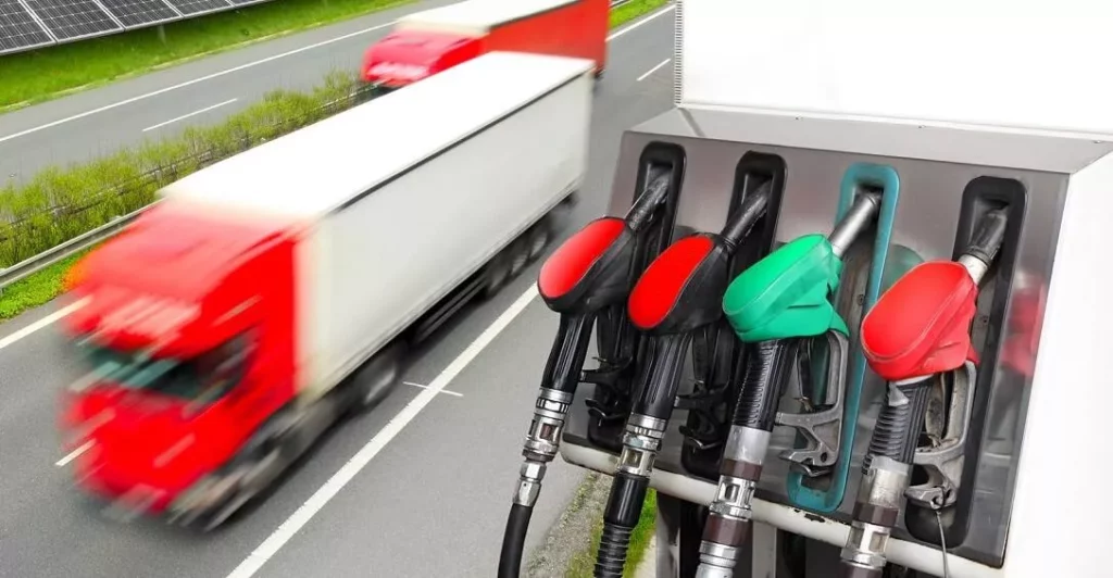 semi trucks driving past fuel pumps